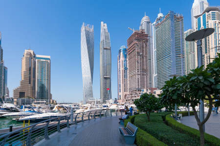 Dubai, UAE - 11.03.2017: Skyline of Dubai Marina on a hot day with clear sky. Skyscrapers, bay, boats, people walking by the water.のeditorial素材