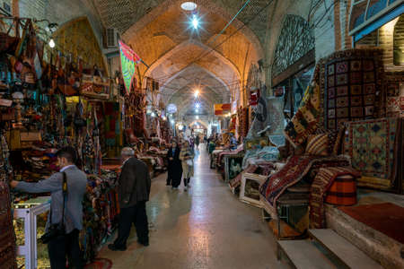 Shiraz, Iran - 04.12.2019: People walking through an alley of Vakil bazaar in Shiraz, Iran. A lot of colorful carpets and lights. Traditional oriental marketplace.のeditorial素材