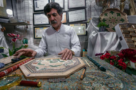 Shiraz, Iran - 04.10.2019: Iranian Khatam master woking behind the desk in his shop in Shiraz, Iran. Old traditinal persian art.のeditorial素材