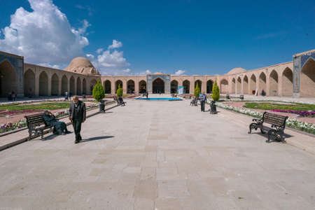 Kerman, Iran - 19.04.2019: People walking around and sitting in the square and bazaar crossroads in the city of Kerman. Oriental urban architecture. Fountain in the middle.のeditorial素材