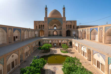 Kashan,Iran-04.08.2019: Courtyard, dome and minarets of Agha Bozorg Mosque in Kashan. Small garden...