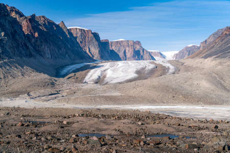 Sun shines above remote arctic valley of Akshayuk Pass, Baffin Island, Canada. Blue sky above...