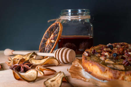 Still life with homemade organic food. Pear pie, jar with honey and dipper, cinnamon, dried fruits, nuts. Healthy breakfast without added sugar.の写真素材