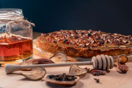 Still life with homemade organic food. Pear pie, jar with honey and dipper, cinnamon, dried fruits, nuts. Healthy breakfast without added sugar.の写真素材