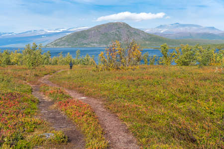 Man walks down to lake deep in the Swedish Lapland. Sunny day and fall colors in Abisko National...