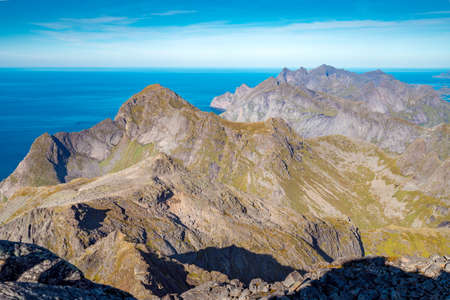 Steep mountains of Lofoten Island on a sunny arctic day. View from the top of Hermannsdalstinden peakHiking mountains of Lofoten, Norway, on a beautiful day of arctic summer. Fjords from above.の写真素材