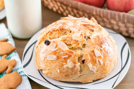 Freshly baked, homemade sweet cake with almonds and raisins on wooden table. Easter loaf. Basket...