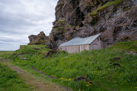 House built into volcanic rock in Southern Iceland. Cloudy day, grass in the foreground.の写真素材