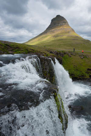 Icelandic waterfall with Kirkjufell mountain in the background. Cloudy day in the north.の写真素材