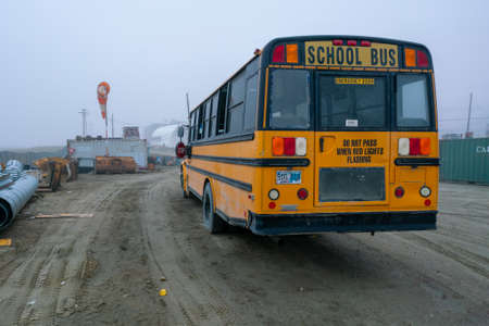 Pangnirtung, Canada - 09.03.2019: Yellow schoolbus in remote Inuit community of Pangnirtung, Nunavut, Baffin Island. Very cold, misty day. The north.のeditorial素材