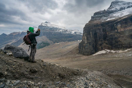 Banff, Canada - 08.30.2018: Man taking a photo of Mt. Lefroy and glacial moraine below at the end of Plain of Six Glaciers trail, Banff National Park. Hiking and exploring Canadian Rockies.のeditorial素材