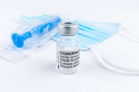 Celadna, Czechia - 05.30.2021: Still life with ampoule of Comirnaty vaccine by Pfizer, blue face...