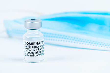 Celadna, Czechia - 05.30.2021: Ampoule of Comirnaty vaccine by Pfizer on white background, with blue...
