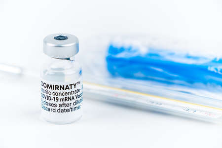 Celadna, Czechia - 05.30.2021: Still life with ampoule of Comirnaty vaccine by Pfizer, blue face mask and medical thermometerのeditorial素材