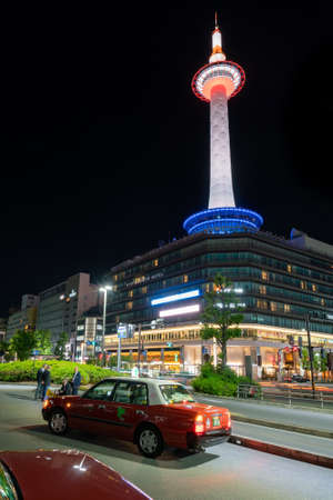 Tokyo, Japan - 15.05.2019: Vertical low angle shot of Kyoto Tower illuminated in different colors in the night from the street below with traditional taxi cars in frontのeditorial素材