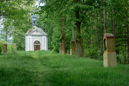 Small Christian Holy Trinity Chapel with Stations of the Cross along the pathway in front of it in Brtniky, Bohemian Switzerland, Czech Republic. Country side chapel by the edge of the woodsの写真素材
