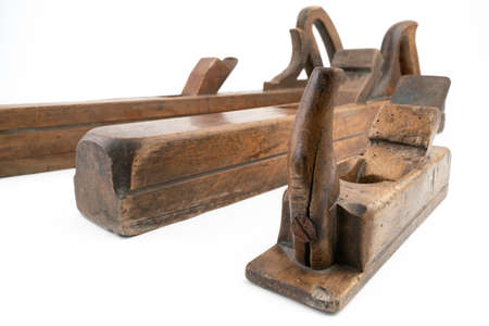 High angle studio shot of three vintage wood planers of different sizes, isolated on white background. Old carpenter tools with wood worm holes. Carpentry concept.の写真素材