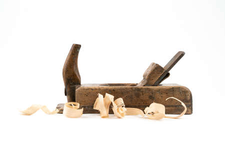 Horizontal low angle studio shot of small vintage wood planed isolated on white background. Old carpenter tool with wood worm holes in it. Thin wooden shavings. Carpentry concept.の写真素材