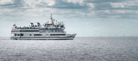 Hel, Poland - 08.01.2021: A passenger boat with people onboard on its way across Baltic sea from Hel to Gdansk on a hazy warm summer day. Summer holiday at the Baltic coast. Cruising ferry.のeditorial素材