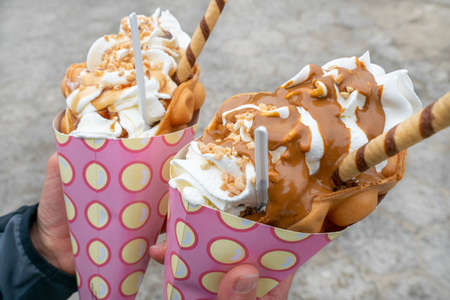 Closeup outdoor shot of Two Bubble waffles, gofry babelkowe, with lots of ice cream in pink paper cones. Famous dessert of Poland. Massive sweet guilty pleasure.の写真素材