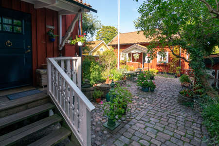 Vastervik, Sweden - 08.23.2021: Wide shot of yard of old, traditional red wooden house in scandinavian style. Sunny summer day in small city garden.のeditorial素材