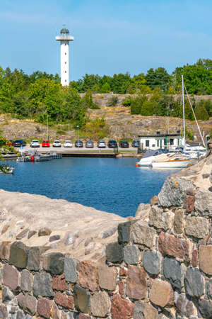 Vastervik, Sweden - 08.22.2021: White slim building of lighthouse with bay in front on a sunny summer day.のeditorial素材