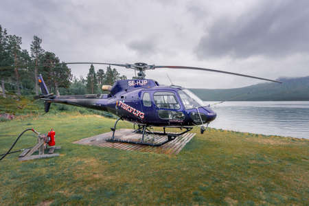 Vietas, Sweden - 08.16.2021: Small blue Fiskflyg helicopter sitting on a wooden board by the lake in bad weather in Stora Sjofallet national park.のeditorial素材