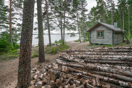 Skuleskogen, Sweden - 08.22.2021: Wooden cabin in the forest of Skuleskogen national park in Sweden with pile of birch firewood in frontの写真素材