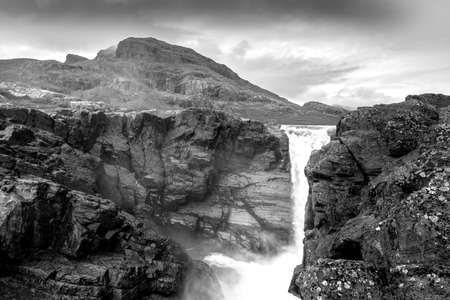 Closeup, wide, black and white low angle shot of mighty Stuor Muorkkegarttje waterfall on Lulealven river on a partly cloudy day of arctic summer. Stora Sjofallet national park, Sweden.の写真素材