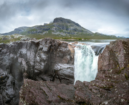 Closeup, wide, low angle shot of mighty Stuor Muorkkegarttje waterfall on Lulealven river on a partly cloudy day of arctic summer. Stora Sjofallet national park, Sweden.の写真素材