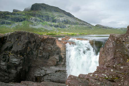 Closeup, wide, low angle shot of mighty Stuor Muorkkegarttje waterfall on Lulealven river on a partly cloudy day of arctic summer. Stora Sjofallet national park, Sweden.の写真素材