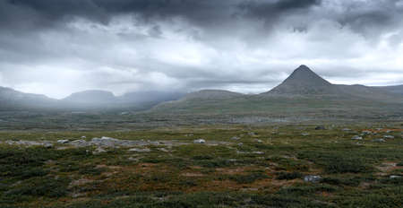 Epic panorama view of Mt Slugga in Swedish Lapland on a very cloudy day of arctic summer. Dramatic weather and landscape of arctic wilderness. Backpacking in Stora Sjofallet National Park.の写真素材