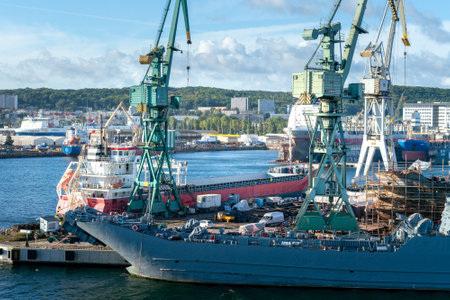 Gdynia, Poland - 09.23.2021: Port cranes loading docked cargo ship on a sunny day.のeditorial素材