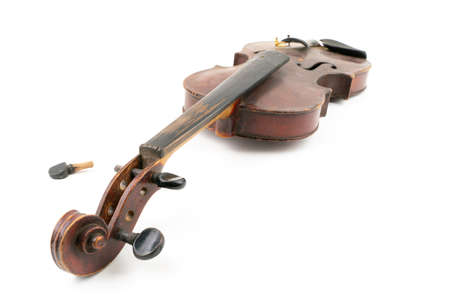 Wide closeup studio shot of old, broken, dust covered violin isolated on white background. Vintage damaged musical instrument. Concept for restoration.の写真素材