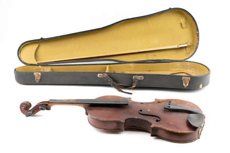 Wide closeup studio shot of old, broken, dust covered violin with its old, scratched case, isolated on white background. Vintage damaged musical instrument. Concept for restoration.の写真素材