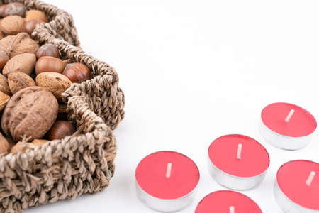 High angle detail studio shot of basket full of mixed nuts and red tea candles isolated on white background. Christmas concept.の写真素材