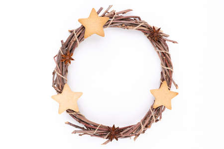 Detail top studio shot of handmade, dry Christmas wreath with gingerbread stars and star anises isolated on white background. Christmas concept. Traditional hand work.の写真素材
