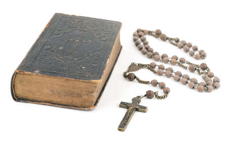 Wide studio shot of very old, vintage Holy Bible with lots of ornaments on the cover and yellow pages and old rosary isolated on white background. Christianity concept. Time of prayer.の写真素材