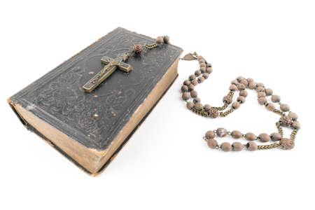 Wide studio shot of very old, vintage Holy Bible with lots of ornaments on the cover and yellow pages and old rosary isolated on white background. Christianity concept. Time of prayer.の写真素材