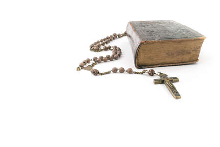 Wide studio shot of very old, vintage Holy Bible with lots of ornaments on the cover and yellow pages and old rosary isolated on white background. Christianity concept. Time of prayer.の写真素材