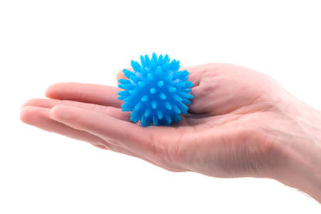 Detail studio shot of blue rubber massage ball lying on palm of a right hand isolated on white background. Contemporary rehabilitation equipment. Physiotherapy tools.の写真素材