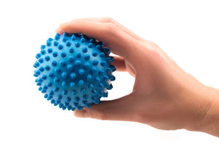 Detail studio shot right hand holding blue rubber massage ball isolated on white background. Contemporary rehabilitation equipment. Physiotherapy tools.の写真素材