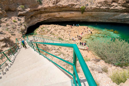 Bimmah, Oman - 04.05.2018: People swimming and hanging around turquoise waters of Bimmah Sinkhole pool, or Hawiyyat Najm, sea water lagoon in Omanian desert.のeditorial素材