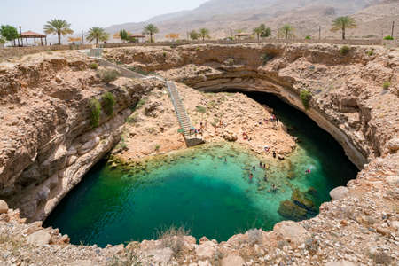 Bimmah, Oman - 04.05.2018: People swimming and hanging around turquoise waters of Bimmah Sinkhole pool, or Hawiyyat Najm, sea water lagoon in Omanian desert.のeditorial素材