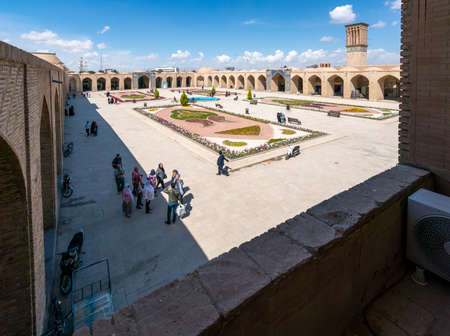 Kerman, Iran - 19.04.2019: People walking around and sitting in the square and bazaar crossroads in the city of Kerman. Oriental urban architecture. Fountain in the middle.のeditorial素材