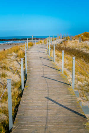 Wooden walkway on a sandy beach of the Dune island, Heligoland, Germany, on a beautiful sunny day of winter. Infinity point on a pathway by the North sea.の写真素材