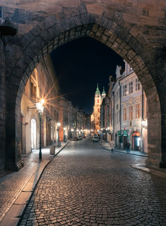 Prague, Czechia - 02.17.2022: View through Mala Strana Tower Bridge arch in the dark night on the Charles Bridge. Center without people. Beautiful historical buildings in central european capital.のeditorial素材