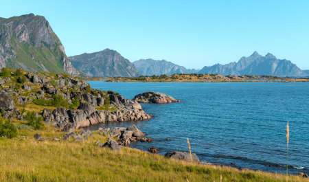 Dramatic Arctic fjord of Lofoten Islands in northern Norway on a beautiful day of arctic summer with dramatic steep rock cliffs and mountains on the horizon. Hiking in remote northern wilderness.の写真素材