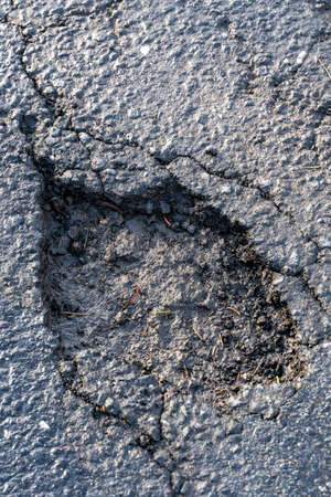 Pot hole in asphalt road. Damaged highway with hole in it. Dangerous holes to be repaired after winter .の写真素材