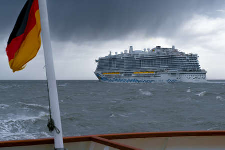 Cuxhaven, Germany - 02.25.2022: Enormous passenger cruising ship Aida on rough water of the North sea on a cloudy day of winter. Dramatic clouds in the sky. Vacation cruising trips.のeditorial素材